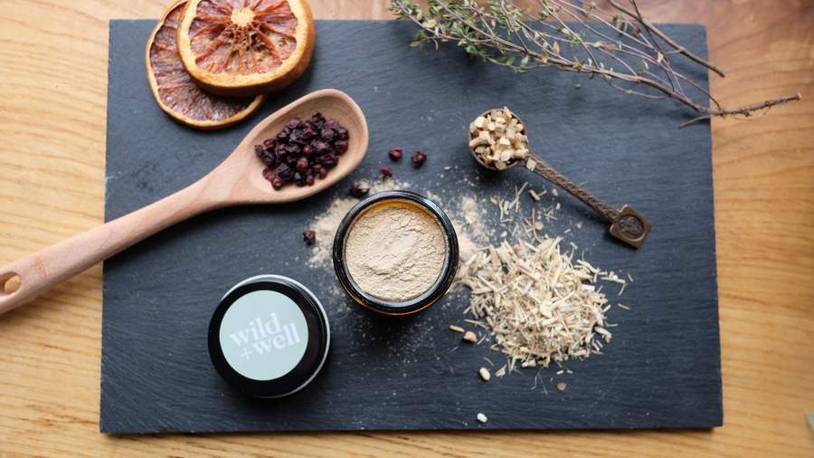 Sage-green tin, an amber jar of golden powder, dried orange slices and two wooden spoons arranged on a slate board